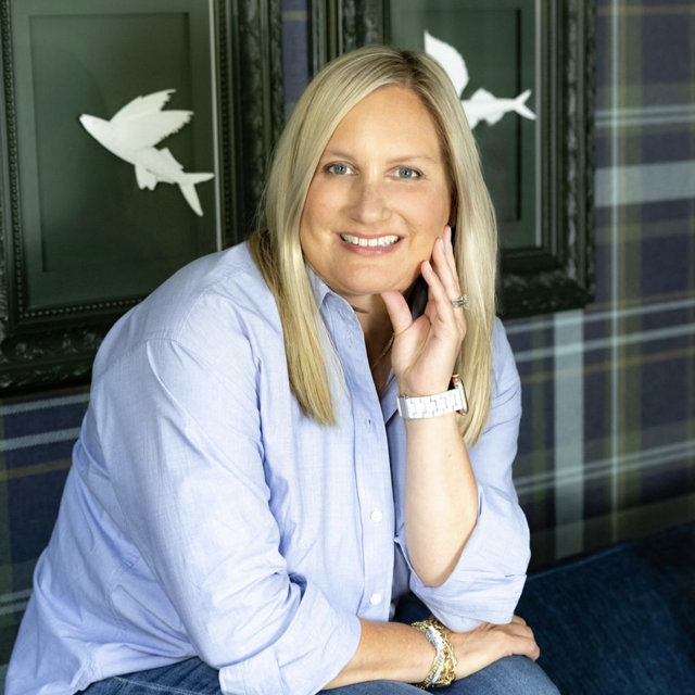 Portrait of a smiling blonde woman wearing a light blue blouse.