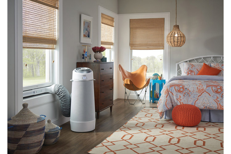 Boho style bedroom with geometric patterned orange and cream area rug orange pouf orange and purple bed leather butterfly chair and a free standing air conditioner by the window how to keep your house cool in the summer