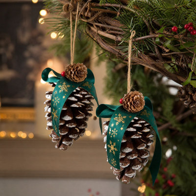 Décoration de Noël des pommes de pin suspendues, décorées de pommes de pin enneigées, d'un ruban vert à flocons de neige et de baies rouges, pour sapin de Noël, mur, porte ou décoration intérieure de Noël