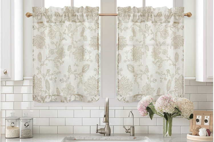 beige floral patterned café curtains hanging on rod above kitchen sink framed by white cabinets and tile backsplash