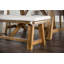 Banc rembourré rustique avec coussin en tissu et base en tréteaux, parfait pour un décor campagnard et des sièges confortables.