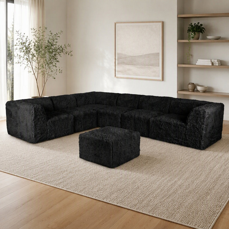 Ensemble de salon modulaire 7 pièces en L, couleur noire, garni de fausse fourrure et de mousse haute densité compressée, avec fauteuils sans accoudoirs et poufs.