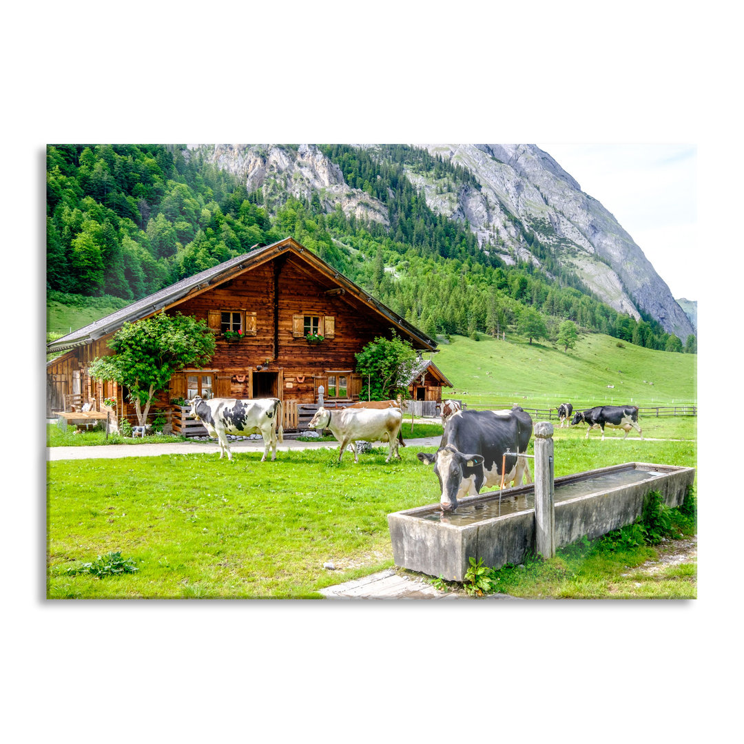 Fotodruck Kühe vor einer Blockhütte auf einer Alm