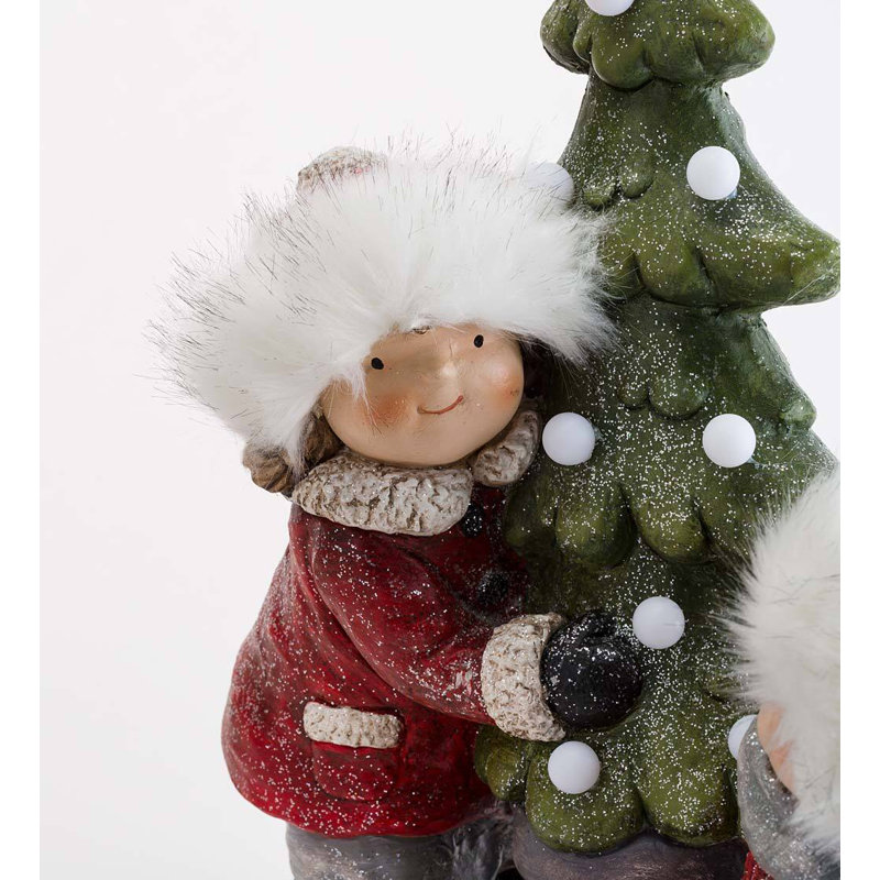 Statue d'enfant avec un sapin de NoÃ«l illuminÃ©