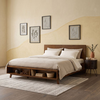 Lit plateforme en bois avec compartiments de rangement ouverts au pied du lit