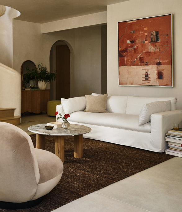 Living room with white couch, abstract art, and marble coffee table.