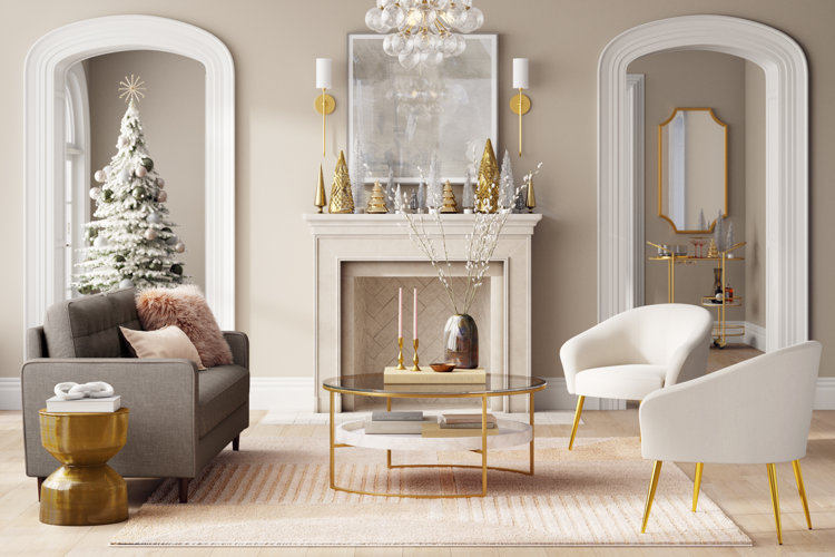 White Christmas living room with a flocked Christmas tree, a gray sofa, and a pair of white chairs with gold chair legs.