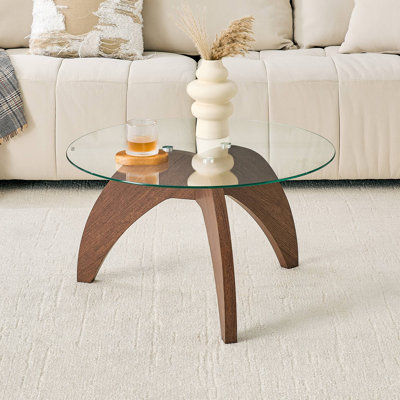 Table basse à pieds triangulaires Creative, d'environ 27,5 pouces de diamètre, avec plateau en verre trempé transparent et panneau de fibres à densité moyenne de couleur noyer. Parfait comme table basse de salon, etc.