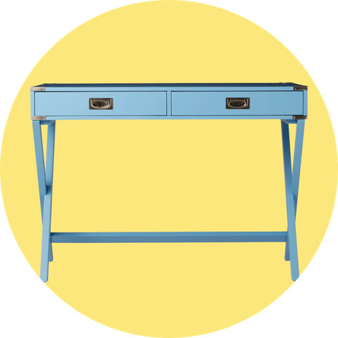 A light blue writing desk with two drawers and X-shaped legs, isolated on a circular yellow background.