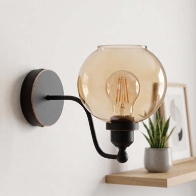 Amber Globe Glass Wall Sconce with Black Curved Arm and Brushed Brass Detail