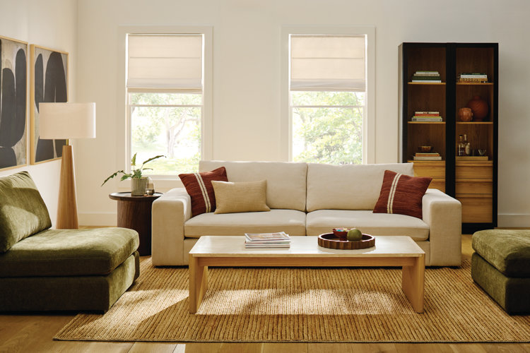 Modern style living room with a white modern sofa two green accent chairs and a light wood rectangular coffee table set up in a conversational U-shaped living room layout