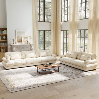 A modular sofa set combining a two-seater and a three-seater, made of velvet fabric, with throw pillows, lumbar pillows and round armrests. Available