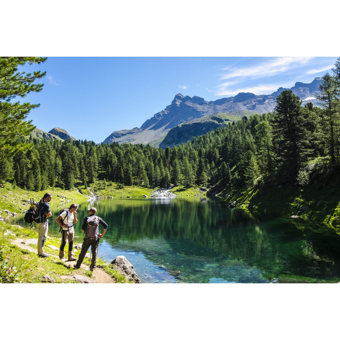 Wanderer auf einem Bergpfad in der Nähe des Alpensees von Deimagine - Kunstdrucke ohne Rahmen auf Leinwand