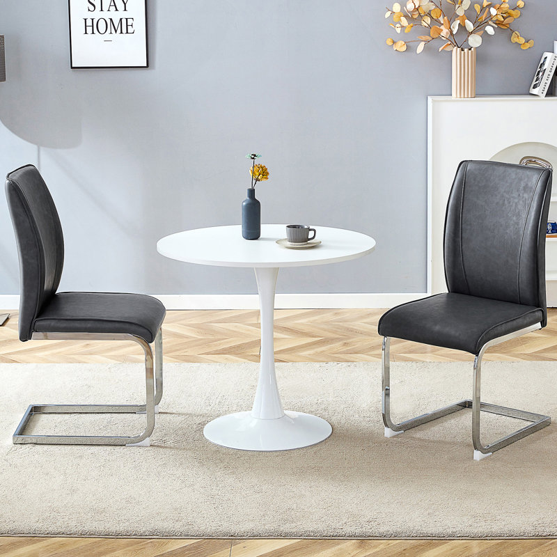 Ensemble de table de salle à manger en forme de sablier avec deux chaises rembourrées en polyuréthane et des pieds arqués en métal pour les espaces compacts.