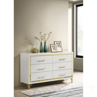 La commode de chambre blanche à 6 tiroirs Chesney aux accents dorés offre beaucoup de rangement et une élégance intemporelle pour les chambres à coucher modernes