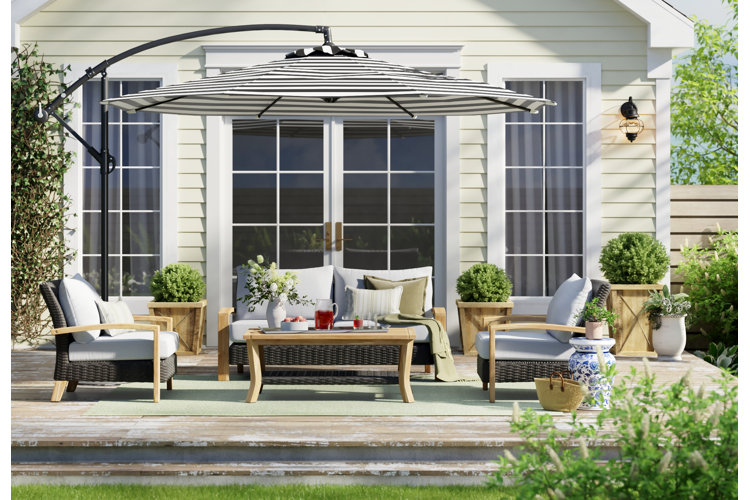outdoor patio sofa set with a light green rug and a striped cantilever umbrella