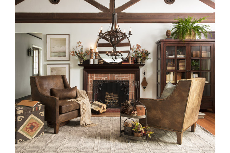 Living room with brown leather armchairs dark wood details, a fireplace, and woven rug.