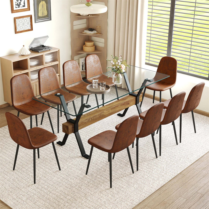 Ensemble de table et chaises de salle à manger moderne et minimaliste avec des pieds en métal en forme de X, une traverse en bois aggloméré et des chaises confortables en techno-tissu.