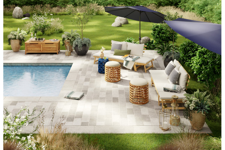 A patio beside an inground pool, with white and gray rectangular tiles and two patio daybeds.