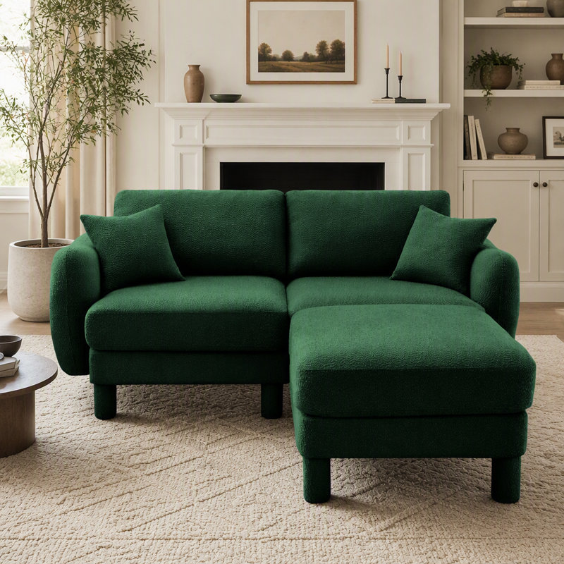 Canapé d'angle 2 places en tissu bouclé, avec accoudoirs originaux en forme de coquillage et pouf amovible, pieds cylindriques recouverts du même tissu, coloris vert.