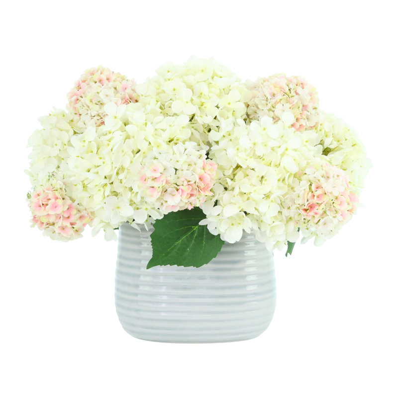 Arrangement d'hortensias et de viornes dans un vase strié