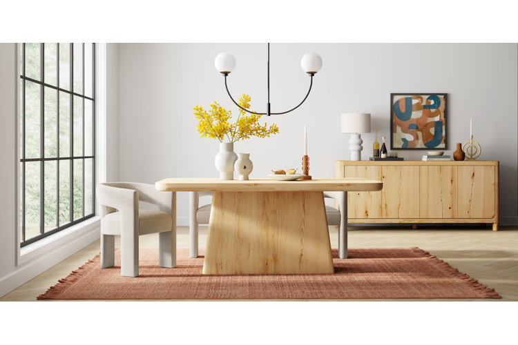 Light colored wood dining room table with a matching light wood buffet table in the background
