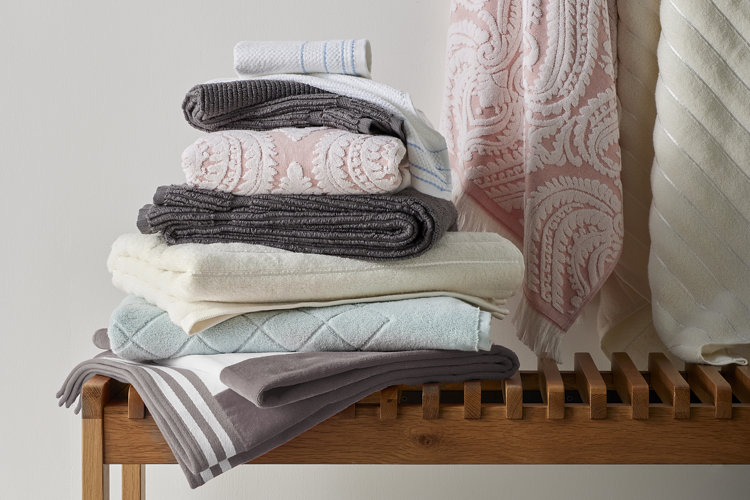 stack of folded towels on top of a wood bench
