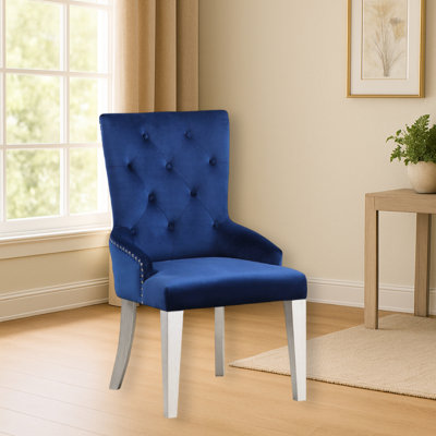 Fauteuil luxueux en tissu bleu avec dossier à boutons et pieds fuselés en bois pour une salle à manger moderne et élégante