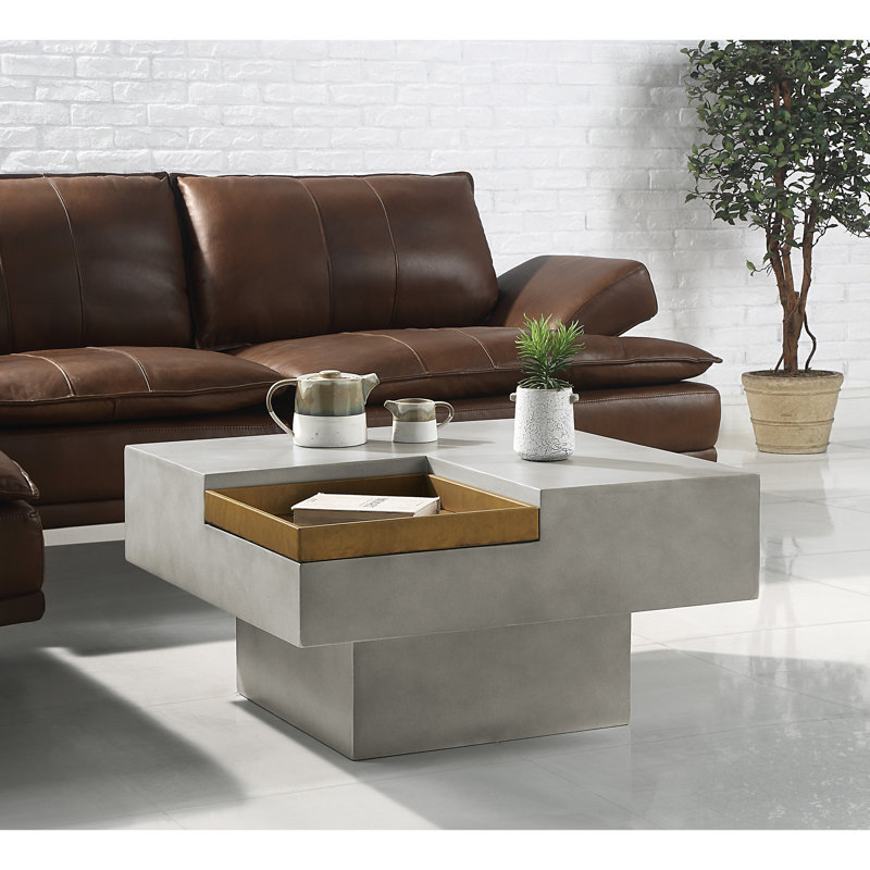 Table basse en ciment de style rustique avec plateau carré et piédestal sur fond gris patiné