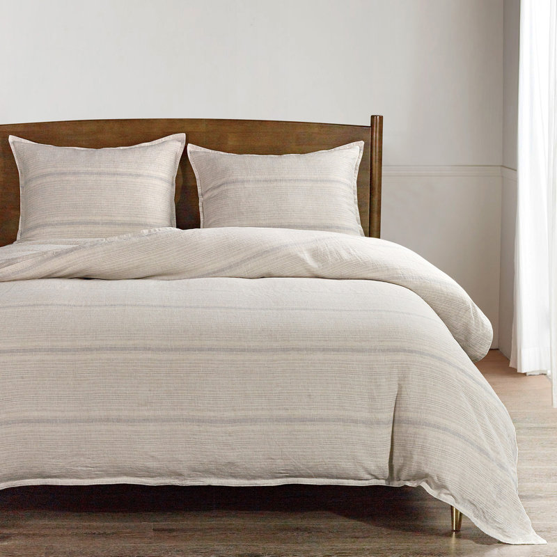 Duvet cover set in beige with horizontal stripes on a bed with a dark wood headboard