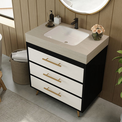 Meuble-lavabo sur pied contemporain avec lavabo en céramique intégré et surface en pierre frittée. Ce meuble-lavabo offre un support stable avec ses pieds en acier thermolaqué et ses poignées encastrées dorées. L'évier a un grand