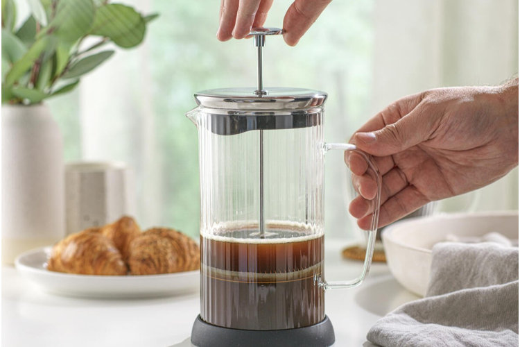 photo of a person's hands demonstrating how to use a French press