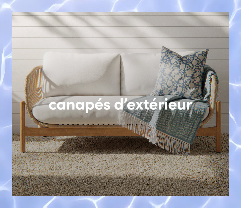 Un canapé d extérieur moderne en bois avec des coussins blancs, un coussin à motifs bleus et une couverture à franges.