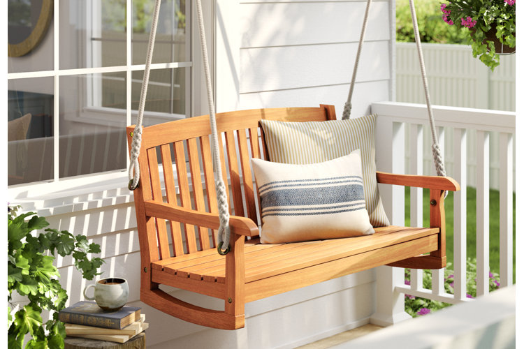A front porch swing with neutral striped pillows