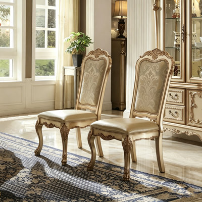 Chaise de salle à manger classique sans accoudoirs, recouverte de cuir doré, avec pieds en bois massif sculpté en forme de griffes.