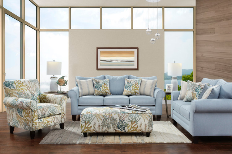 coastal-style living room with light blue sofas, patterned armchair and matching ottoman, layered lighting, ocean-inspired decor