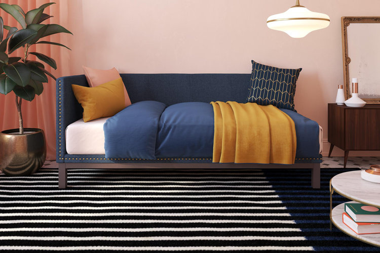 navy blue upholstered daybed with a blue comforter and yellow accent throws in a boho-style living room