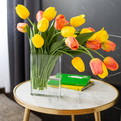 Mélange réel de tulipes hollandaises orange et jaunes, illusion d'eau de tous les jours dans un vase rectangulaire moderne