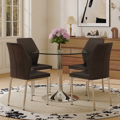 Ensemble de table et de chaises. Une table de salle à manger ronde en verre trempé transparent de 35 po - Support et base en métal argenté. Assorti de 4 chaises de salle à manger en polyuréthane noir à haute résilience avec pieds en métal argenté.