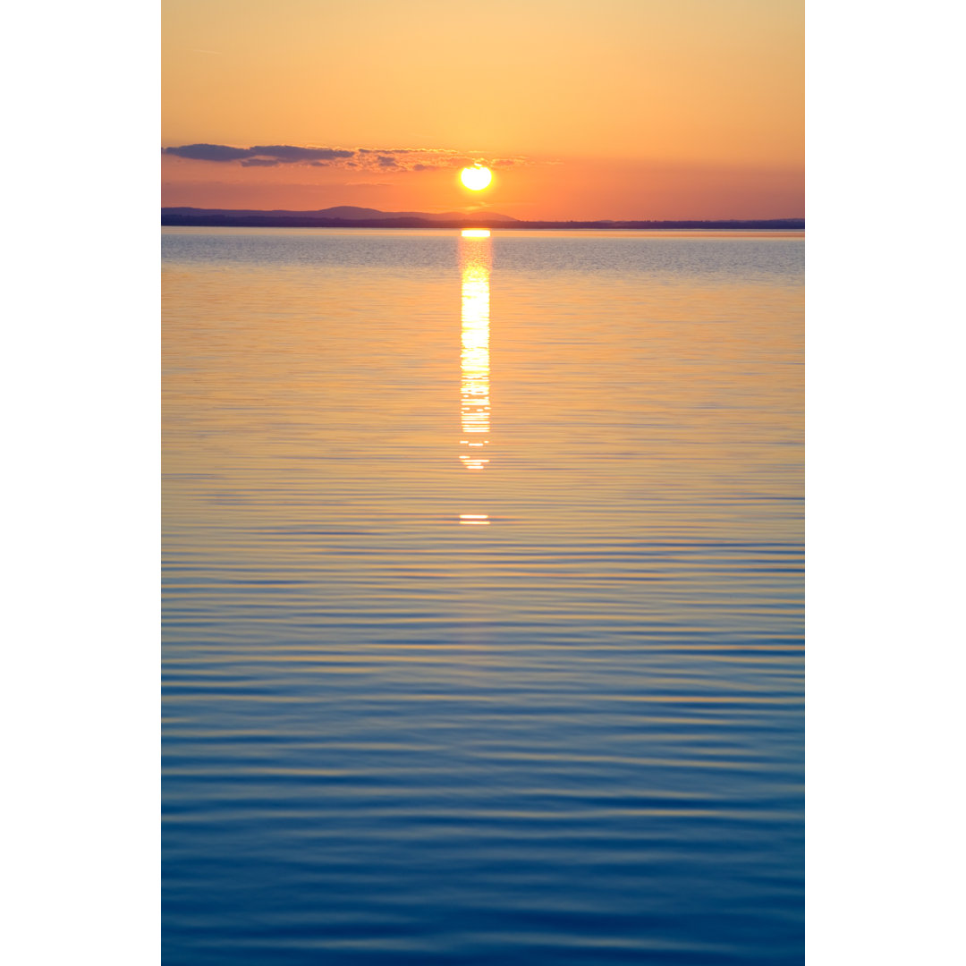 Plätschern auf dem Wasser vor der orangefarbenen untergehenden Sonne