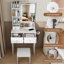 Petit meuble-lavabo moderne avec 3 modes d'éclairage DEL à luminosité réglable, 3 tiroirs et plusieurs tablettes de rangement ouvertes, un support pour sèche-cheveux et une prise de courant, et un fauteuil à vêtements-870978342