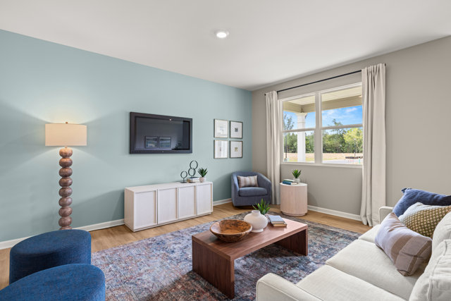 Living room with blue accent wall, TV, white console table, and patterned rug.