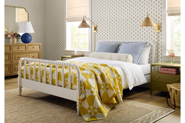 small bedroom lighting ideas a modern small bedroom with gold swing arm wall sconces and blue table lamp on a wooden dresser the room has vintage patterned wallpaper, a white bed with a bobbin carved frame and white blue and yellow bedding