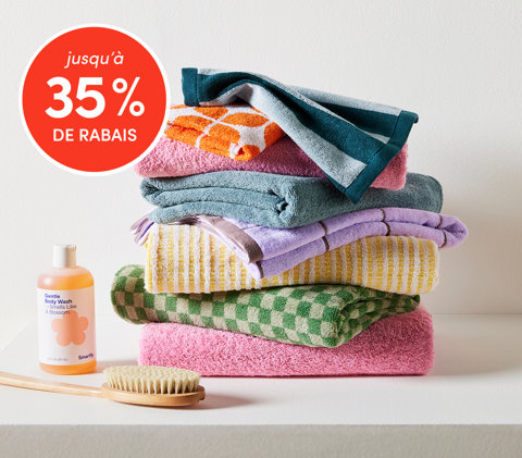 Essentiels de salle de bain jusqu'à 35 % de rabais avec serviettes colorées empilées, gel douche et brosse
