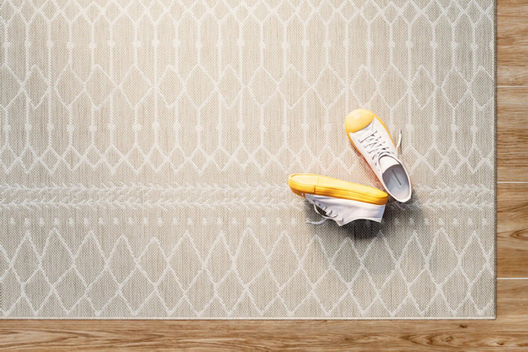 beige flatweave area rug with a white geometric pattern over light hardwood floors