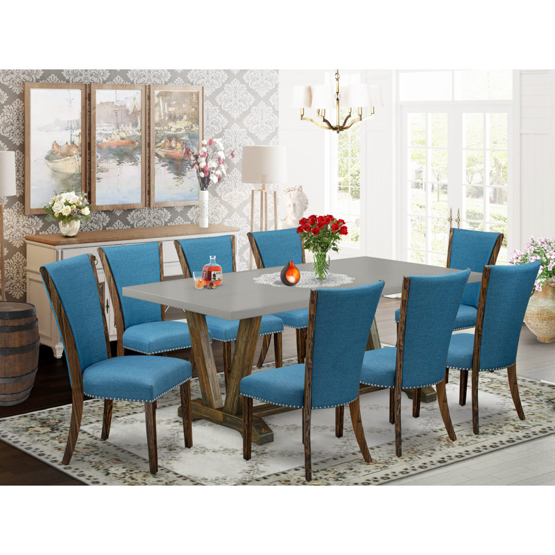 Cet ensemble de table de salle à manger de 9 pièces comprend une table moderne en ciment et 8 chaises de salle à manger en tissu de lin bleu avec dossier haut - finition jacobine patinée.