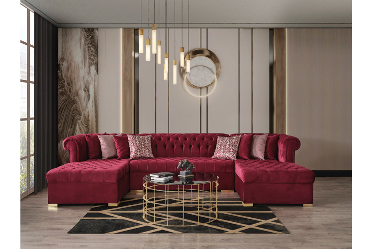glam-style living room with a cherry-red, velvet sectional sofa, round gold coffee table, and glam chandelier