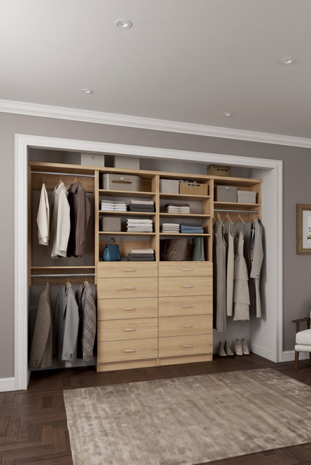 Light wood closet organization system with hanging rods, shelving, and ten drawers installed in a reach-in closet.