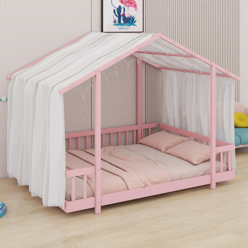 Un lit plateforme avec une structure en forme de maison, un ciel de lit transparent et des lumières scintillantes crée un refuge douillet pour les enfants.