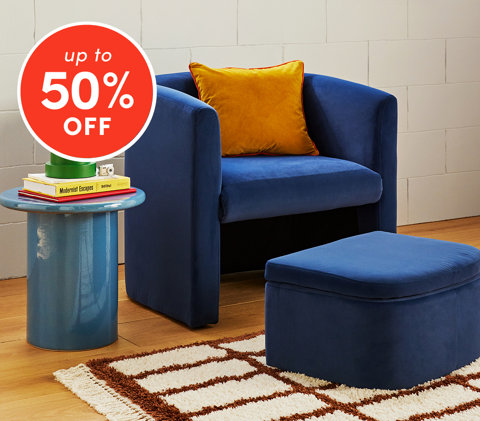 Chairs up to 50% off featuring blue velvet armchair with orange pillow and matching ottoman